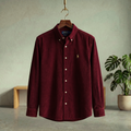 Burgundy corduroy button-up shirt with long sleeves and collar, chest logo.