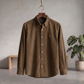 Brown corduroy button-up shirt with collar and long sleeves, hanging on a hanger.