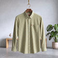 Yellow plaid shirt on a hanger against a gray wall with a plant in the background